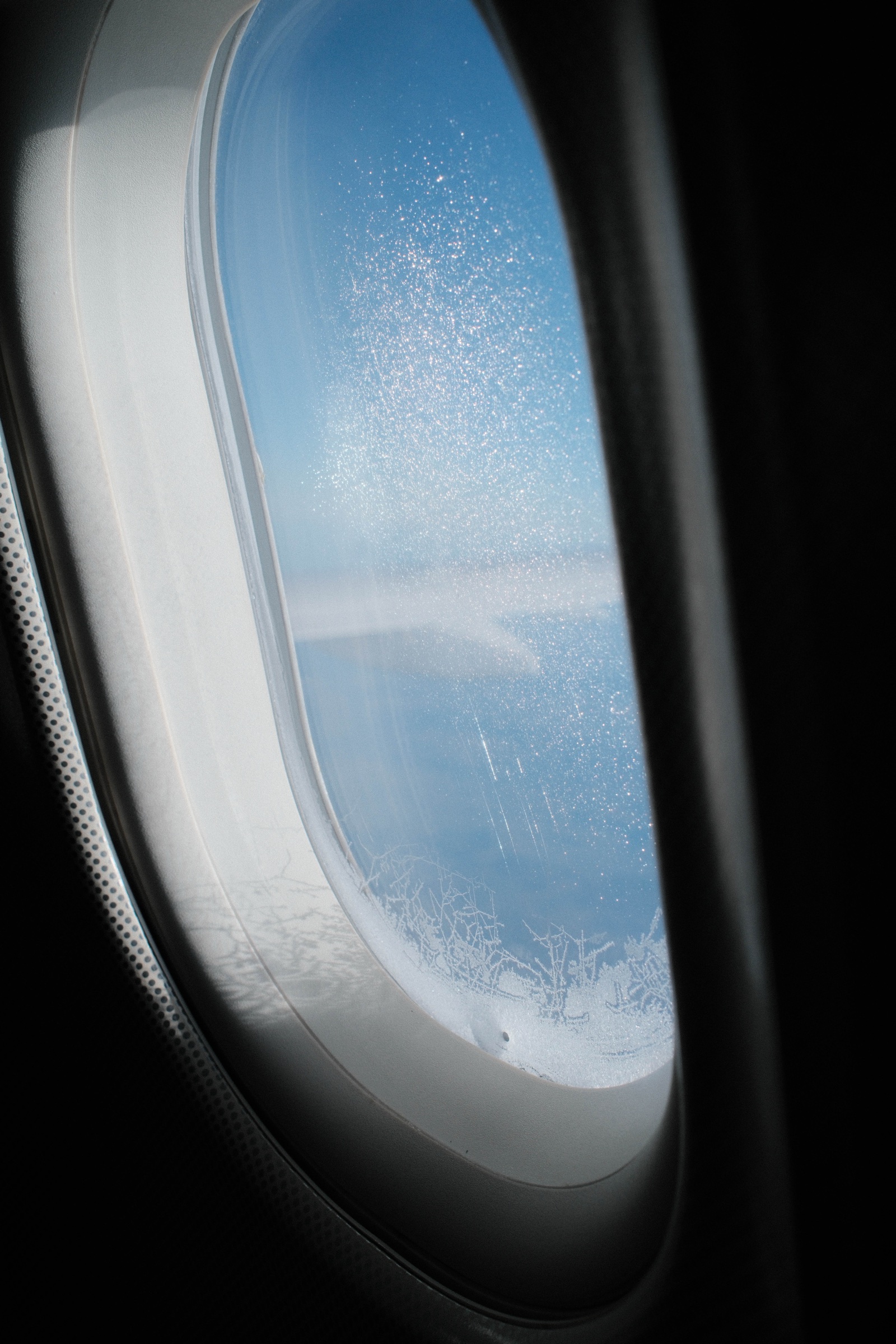 Blue sky framed by the oval shape of an airplane window