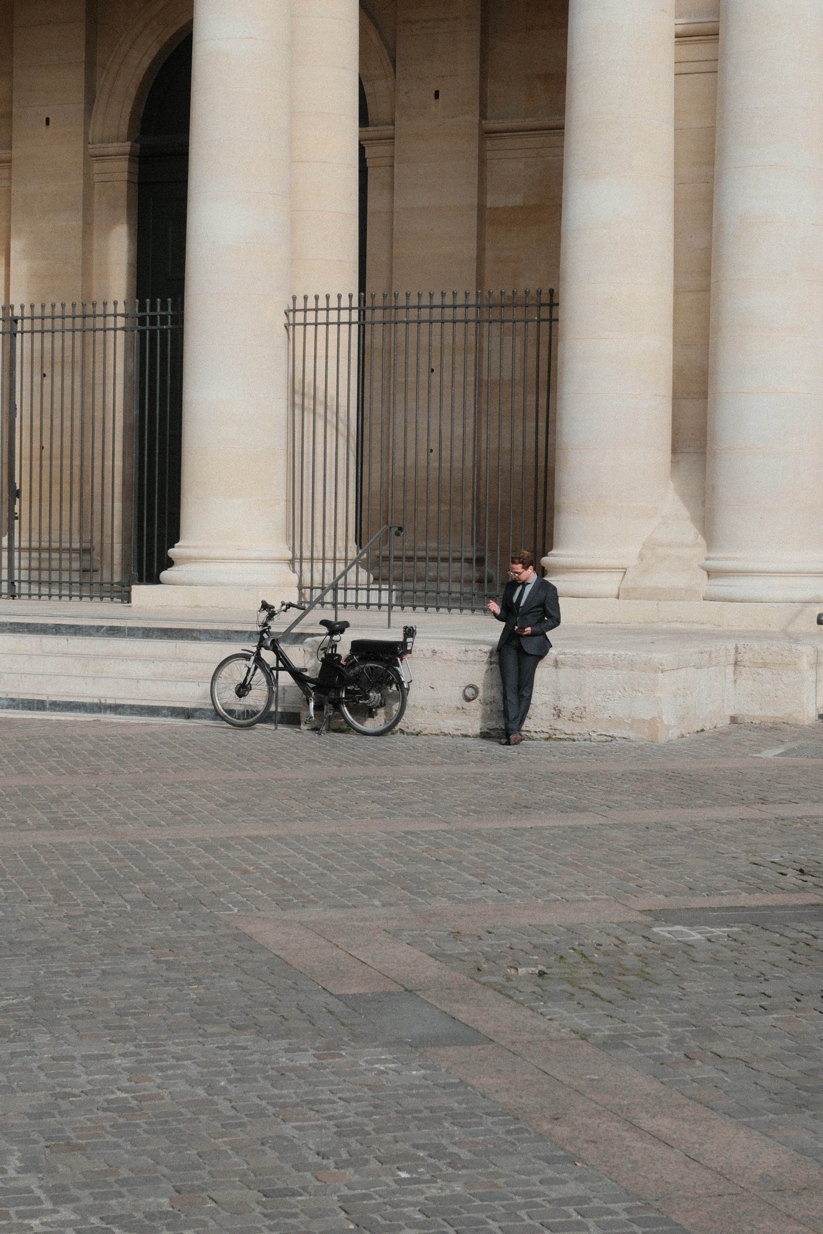 A bicycle parked beside monumental stone columns