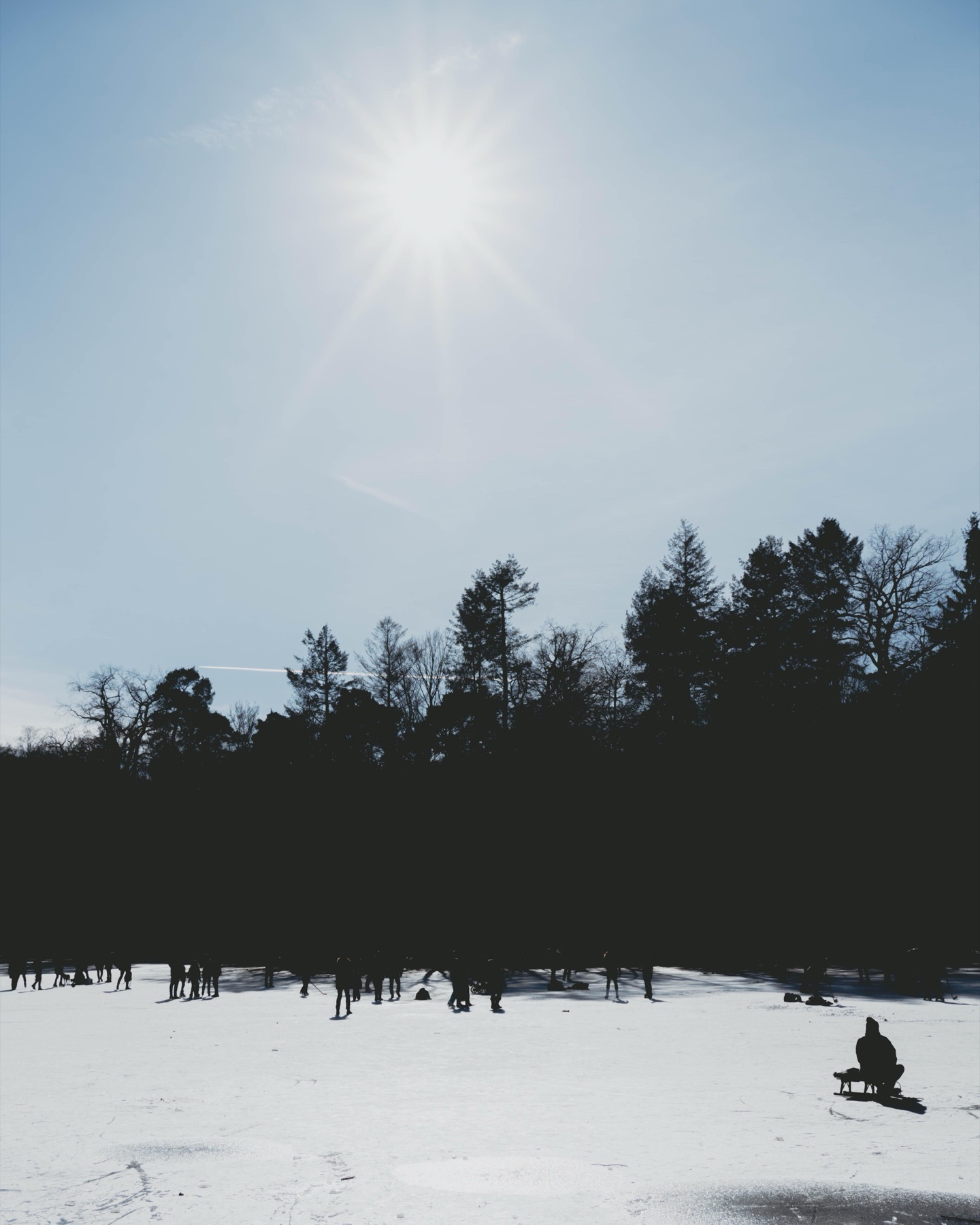 A lone figure crossing a bright snowfield beneath the winter sun