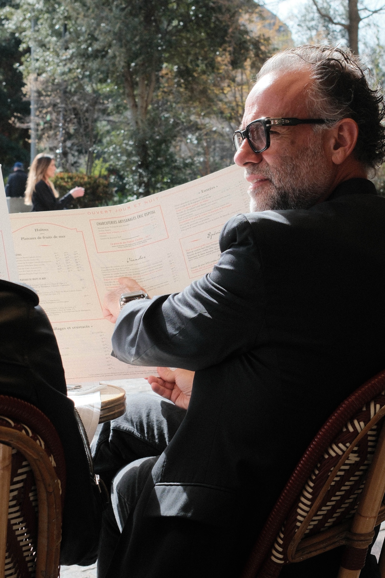 A man reading alone at an outdoor café table