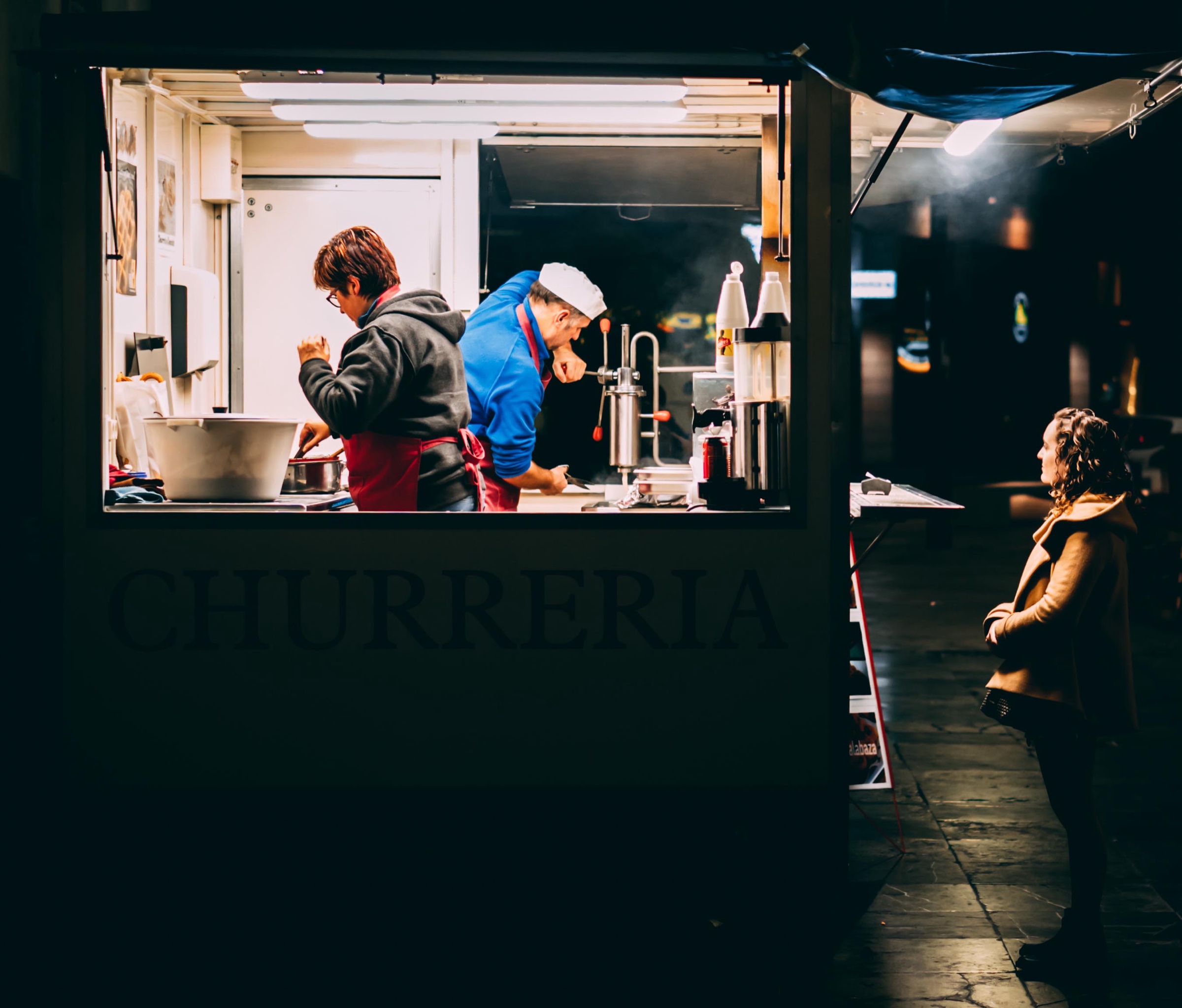 People gathered around a small food kiosk at night