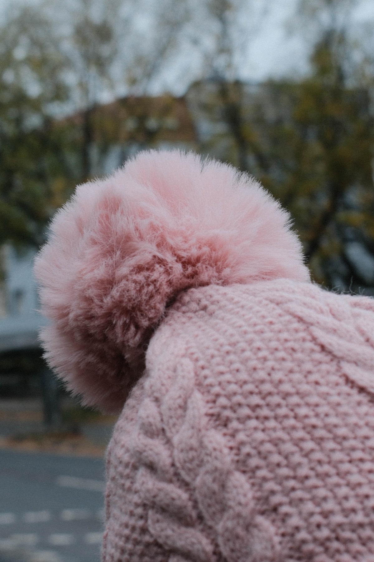 A soft pink pom-pom hat passing through a crowd