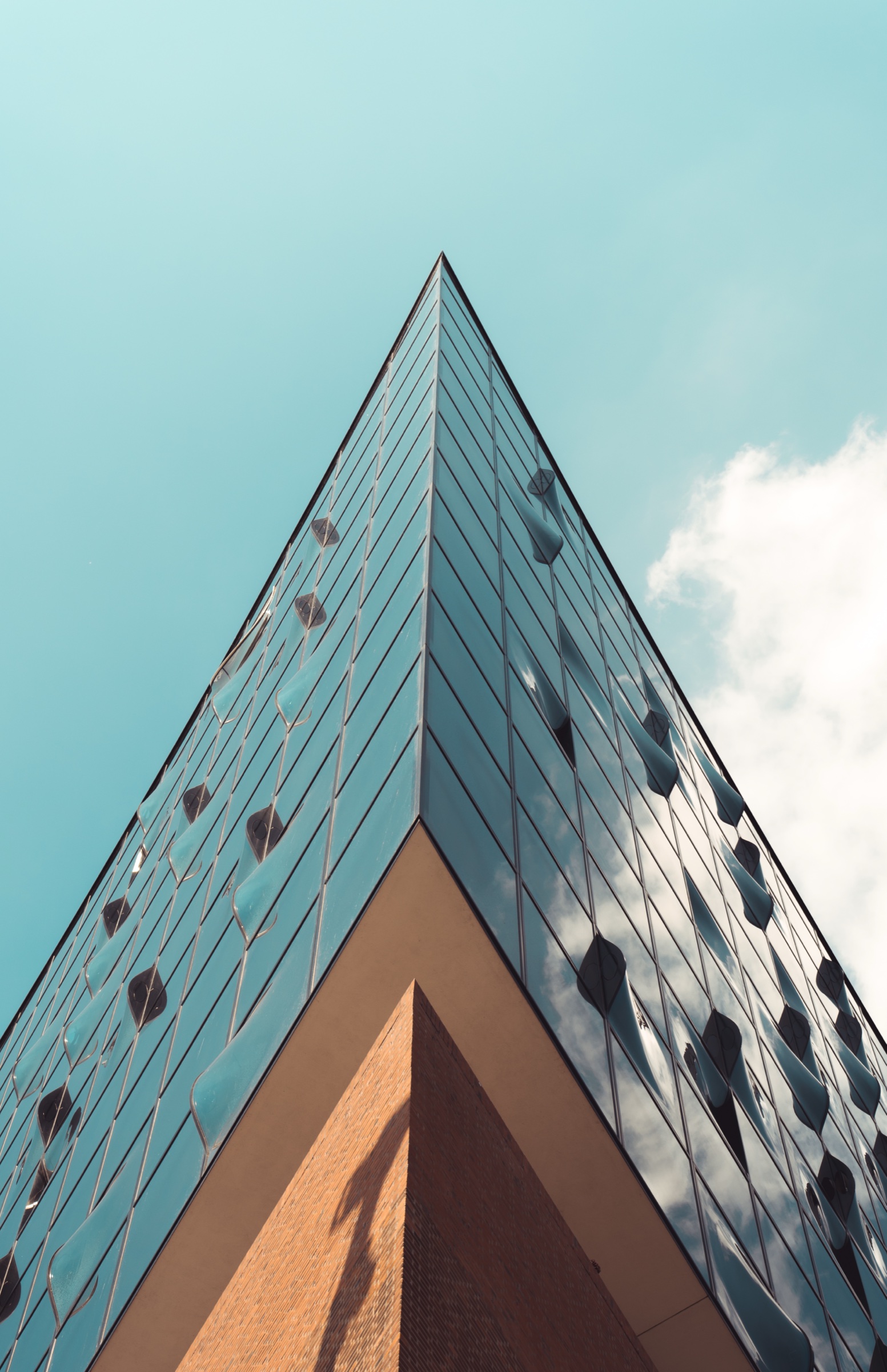 Upward view of the Elbphilharmonie facade against a pale blue sky