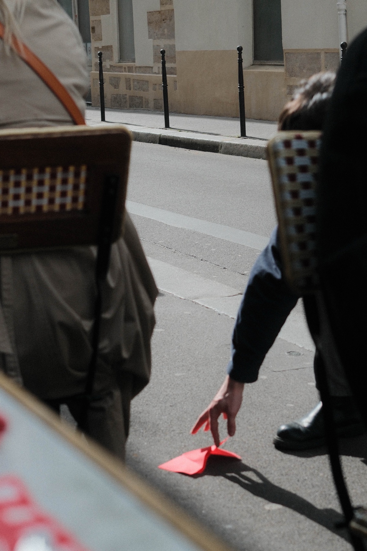 A bright red sheet held low between café chairs